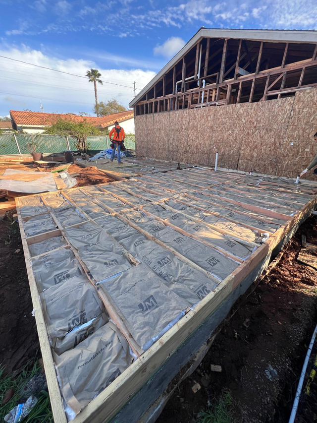 House foundation in progress with cement base and wood framework.