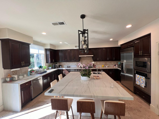 Beige and brown finished kitchen with stylish lighting and a modern dining table.
